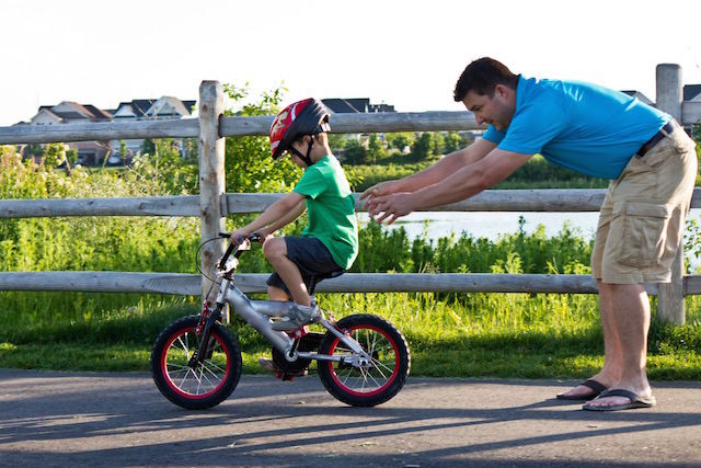 Parent teaching a child to ride a bicycle
