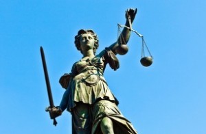 Statue holding the scales of justice against a blue sky